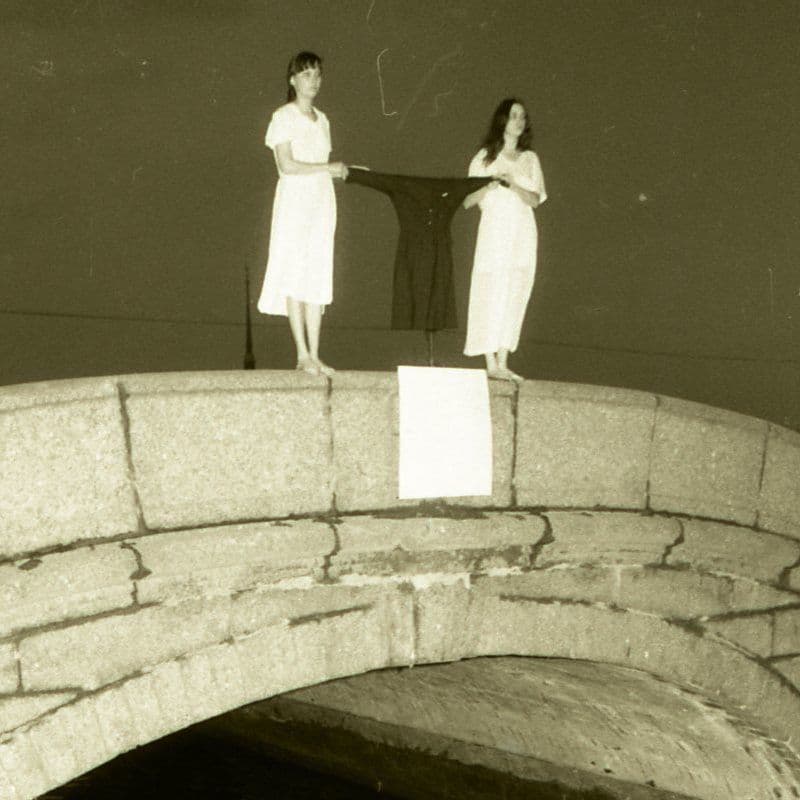 Обложка выпуска. Фотография, сделанная ночью. Две девушки в белых платьях стоят на краю каменного моста через канал. Между ними растянуто платье темного цвета. Они держат его за разные рукава. 